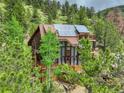 Stunning exterior view of a multi-story home featuring solar panels nestled among tall trees and greenery at 1575 York Gulch Rd, Idaho Springs, CO 80452