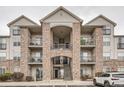 Multi-story condominium featuring a stone facade, balconies, and accessible parking at 7292 S Blackhawk St # 2-204, Englewood, CO 80112