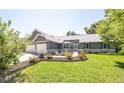 Charming gray house boasts an attached 2-car garage and a beautifully landscaped front yard with grass at 995 Chase St, Lakewood, CO 80214