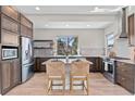 Bright kitchen with a central island, stainless steel appliances, wooden cabinets, and a large window at 15525 W La Salle Ave, Lakewood, CO 80228
