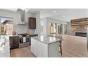 Open-concept kitchen featuring an island with seating and modern appliances next to a living room with a fireplace at 15525 W La Salle Ave, Lakewood, CO 80228