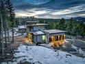Aerial view of a modern house with a three-car garage surrounded by lush greenery and a beautiful landscape at 11505 Conifer Ridge Dr, Conifer, CO 80433