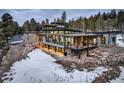 Expansive home featuring multi-level terraces, stone accents, and walls of windows showcasing amazing views at 11505 Conifer Ridge Dr, Conifer, CO 80433