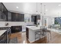 Modern kitchen with dark cabinets, stainless steel appliances, a large island, and hardwood floors at 1828 Blue Oak Ct, Castle Rock, CO 80104