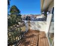 Sunny balcony with wood deck, metal railing, and views of trees and other buildings at 7835 Barbara Ann Dr # C, Arvada, CO 80004