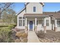 Home featuring a blue front door, stone accents, landscaping, and large windows with white shutters at 8300 Fairmount Dr # J105, Denver, CO 80247