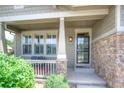 Inviting covered front porch with stone accents and a cozy seating area at 8594 W Quarto Ave, Littleton, CO 80128