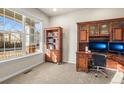 Cozy home office with built-in wooden bookcase, a desk, dual monitors, and natural light at 1271 Sky Rock Way, Castle Rock, CO 80109