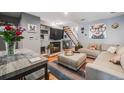 Cozy living room with a fireplace, plush sectional, modern decor, hardwood floors, and open staircase at 1150 Inca St # 43, Denver, CO 80204