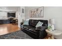 Living room features a dark leather sofa, hardwood floors and modern decor at 8187 Martin Luther King Blvd, Denver, CO 80238