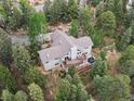 Aerial view of a home nestled among lush trees, with a deck and hot tub at 30382 Kings Valley East, Conifer, CO 80433