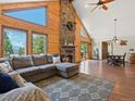 Spacious living room with wood-paneled walls, a large stone fireplace, and mountain views at 30382 Kings Valley East, Conifer, CO 80433