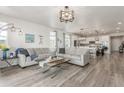 Bright living room featuring wood floors, sofas, and open concept to kitchen and dining space at 12513 Shore Point St, Firestone, CO 80504