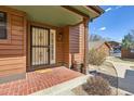 Close-up of a charming entryway with brick accents, a secure screen door, and inviting decor at 8040 Holland Ct # C, Arvada, CO 80005