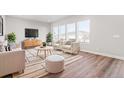 Bright living room with hardwood floors, large windows, and stylish neutral furniture at 21097 E 62Nd Dr, Aurora, CO 80019