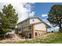 A beautiful multi-story home with a patio and stone stairs nestled into a hill with mature trees at 10554 Tanglewood Rd, Franktown, CO 80116