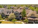 Aerial view of a gray two-story home with landscaping, a picket fence, and nestled among lush greenery in a neighborhood at 2924 Fulton St, Denver, CO 80238