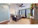Open living room featuring a ceiling fan, large windows, and a comfortable sofa with a view to dining and kitchen areas at 13144 E 109Th Pl, Commerce City, CO 80022