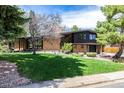 Well-maintained front yard with lush green grass, mature trees, and brick house with large windows at 6975 S Chase Ct, Littleton, CO 80128