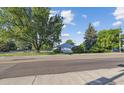 A cozy home featuring mature trees, a green lawn, and a chain link fence at 2105 S Irving St, Denver, CO 80219