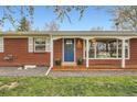 Welcoming red brick ranch with a cheerful blue door, cozy covered porch, and attractive landscaping at 9580 W 12Th Pl, Lakewood, CO 80215