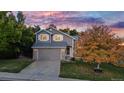 Two-story home with gray siding, a two-car garage, and a well-manicured lawn at 6512 S Taft Way, Littleton, CO 80127