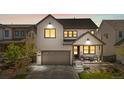 Charming two-story home with landscaped front yard, covered porch, and attached two car garage at dusk at 9140 Moondance Sw Dr, Littleton, CO 80125