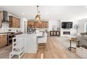 Open concept kitchen flows into living room with fireplace and contemporary furnishings under bright pendant lights at 9140 Moondance Sw Dr, Littleton, CO 80125