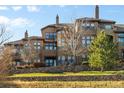 Multi-story home featuring multiple balconies and lots of windows overlooking a green lawn and rock wall at 7882 Vallagio Ln, Englewood, CO 80112