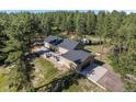 Expansive aerial shot showcasing the home's layout, garage, outdoor patio, and surrounding wooded area at 11044 Conestoga Pl, Franktown, CO 80116