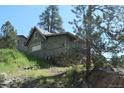 Exterior side view of a home with a rock wall and grassy hill at 28127 Knowles Rd # Ab&C, Evergreen, CO 80439