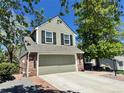 Two-story home featuring a brick facade, siding, attached garage, and mature landscaping at 9867 W Berry Dr, Littleton, CO 80123