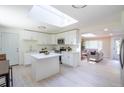 Updated kitchen with skylight, white cabinets, island, and stainless appliances seamlessly connects to a cozy living space at 5041 S Julian St, Englewood, CO 80110