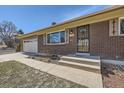 Close-up of home's brick facade, steps leading to front door, attached garage on left at 1701 S Valentine Way, Lakewood, CO 80228