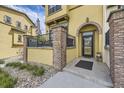 Inviting townhome entrance featuring brick columns, a black metal railing, and manicured landscaping at 15576 W Washburn Cir, Lakewood, CO 80228