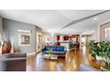 Open-concept living room features hardwood floors, a blue leather couch, and seamless transition to the kitchen at 6945 N Fargo Trl, Littleton, CO 80125
