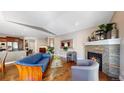 Living room with fireplace, blue leather couch, hardwood floors, and kitchen access at 6945 N Fargo Trl, Littleton, CO 80125