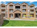 Well-maintained condo exterior with stone accents, balconies, and vibrant green grass at 7440 S Blackhawk St # 14-103, Englewood, CO 80112