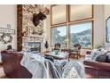 Inviting living room featuring a stone fireplace, large windows with mountain views, and leather furniture at 9659 S Turkey Creek Rd, Morrison, CO 80465