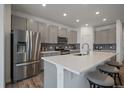 Modern kitchen with stainless steel appliances, gray cabinetry, a center island with breakfast bar seating, and wood floors at 18001 Herrera Dr, Parker, CO 80134