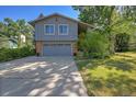 Two-story house with a gray exterior, brick accents, a spacious driveway, and a well-maintained lawn at 6034 S Niagara Ct, Centennial, CO 80111