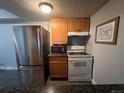 Functional kitchen with stainless steel refrigerator, range and microwave, complemented by granite countertops and wooden cabinets at 10785 W 63Rd Pl # 105, Arvada, CO 80004