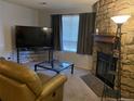 Cozy living room featuring a stone fireplace, large TV, and comfortable seating at 10785 W 63Rd Pl # 105, Arvada, CO 80004