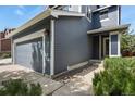 A close-up of a two-story house with blue siding, a gray garage door and landscaping at 5453 S Quatar Ct, Aurora, CO 80015