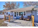 Inviting front porch with wood chairs, a small table, and grey painted wood at 1193 S Umatilla St, Denver, CO 80223
