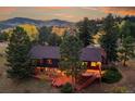 Stunning exterior of home at twilight, featuring large deck, mature trees, and a beautiful yard at 21849 Cabrini Blvd, Golden, CO 80401