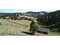 Scenic landscape features rolling hills, a lush green valley, and a few houses and sheds scattered throughout at 21849 Cabrini Blvd, Golden, CO 80401