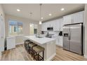Modern kitchen with white cabinets, stainless steel appliances, and a spacious island with seating at 6745 S Tempe Ct, Aurora, CO 80016