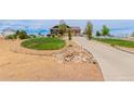 A view of the home showing mature landscaping, a long driveway and decorative rock features at 10653 E 163Rd Ct, Brighton, CO 80602