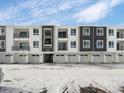 Modern townhome building with attached garages and snowy parking area at 6153 N Ceylon St # 201, Denver, CO 80249